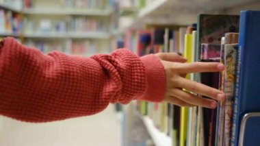 Küçük çocuk kütüphanede kitap seçiyor.