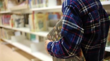 Kitaplı küçük çocuk kütüphanede yürüyor.