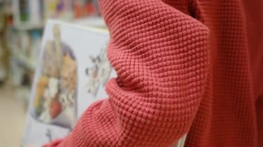 Kitaplı küçük çocuk kütüphanede yürüyor.