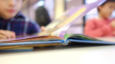 Bulanık küçük çocuk masada kitap okuyor.