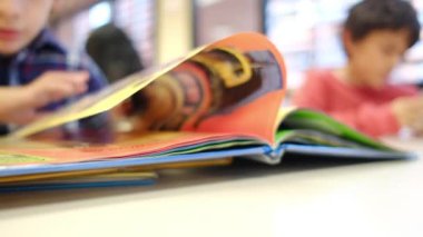 Bulanık küçük çocuk masada kitap okuyor.