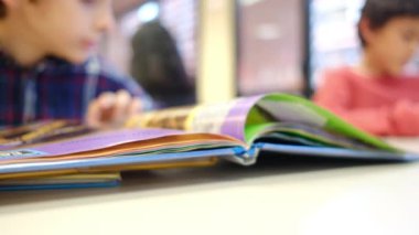 Bulanık küçük çocuk masada kitap okuyor.