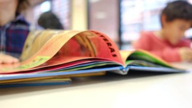 Bulanık küçük çocuk masada kitap okuyor.