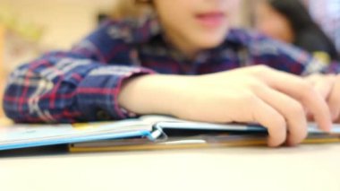 Bulanık küçük çocuk masada kitap okuyor.