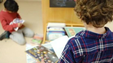 Küçük çocuklar kütüphanede kitap seçiyor.