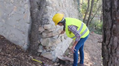 Üniforma giyen ve kask takan kadın işçiler güneşli bir günde betonla tuğla bina onarıyor.