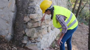 Üniforma giyen ve kask takan kadın işçiler güneşli bir günde betonla tuğla bina onarıyor.