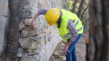 Üniforma giyen ve kask takan kadın işçiler güneşli bir günde betonla tuğla bina onarıyor.