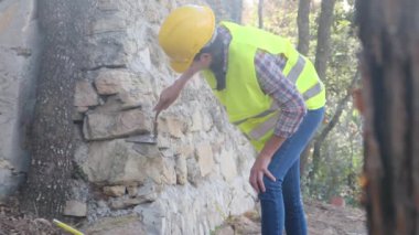 Üniforma giyen ve kask takan kadın işçiler güneşli bir günde betonla tuğla bina onarıyor.