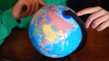 Küçük çocuklar masadaki Dünya gezegenini inceliyor.