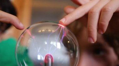 Küçük çocuklar masada yıldırımla plazma topu çalışıyor.