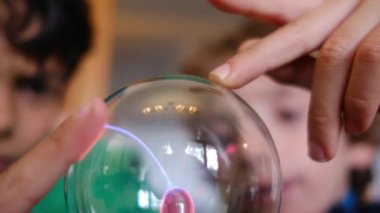 Küçük çocuklar masada yıldırımla plazma topu çalışıyor.