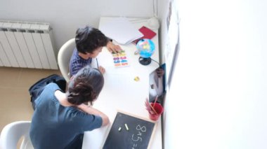Annesinin, oğlunun evde matematik ödevi yapmasına yardım ettiği en iyi manzara.