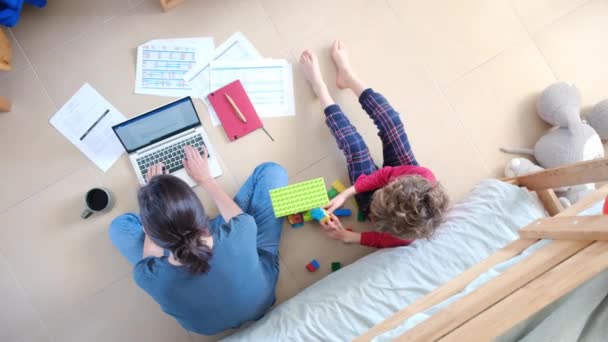 Top Kilátás Dolgozik Laptop Fia Játszik Játék Építőkockák Padlón Otthon — Stock videók