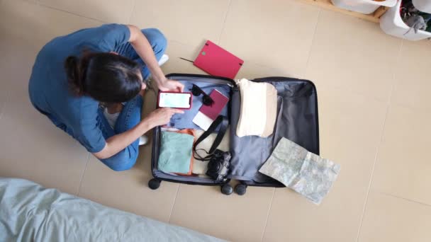 Visão Superior Viajante Feminino Usando Smartphone Enquanto Coleta Coisas Mala — Vídeo de Stock