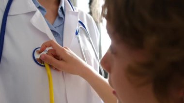 Klinikte steteskopla kadın doktoru muayene eden çocuk hasta.