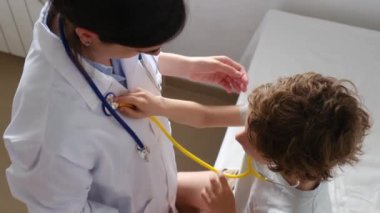 Klinikte steteskopla kadın doktoru muayene eden çocuk hasta.