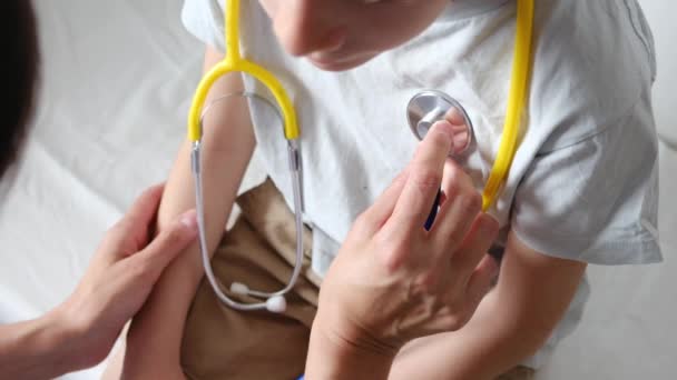 診療所でステスコープを患う少年の心拍をチェックする女性医師 — ストック動画