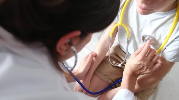 診療所でステスコープを患う少年の心拍をチェックする女性医師 — ストック動画