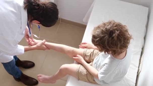 Female Doctor Examining Leg Boy Patient Clinic — Stock Video