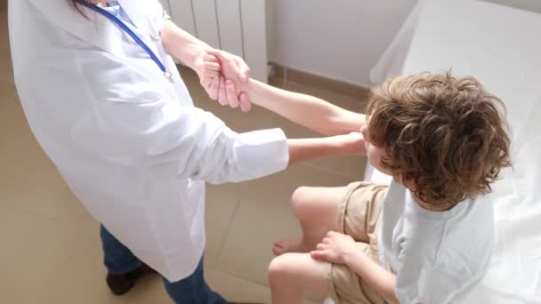 Kvinnlig Läkare Undersöker Hand Pojke Patient Kliniken Royaltyfri Stockvideo