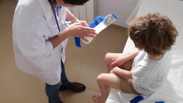 Вид Зверху Жінку Лікарку Яка Готує Ортез Покладання Ногу Хлопчика — стокове відео