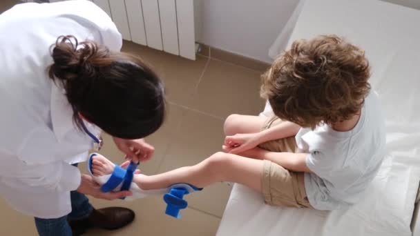 Žena Lékař Uvedení Derotační Ortézy Zlomeninu Chlapecké Nohy Klinice — Stock video