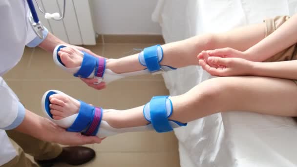 Жінка Лікар Яка Вивчає Ноги Пацієнта Носять Ортоз Клініці — стокове відео