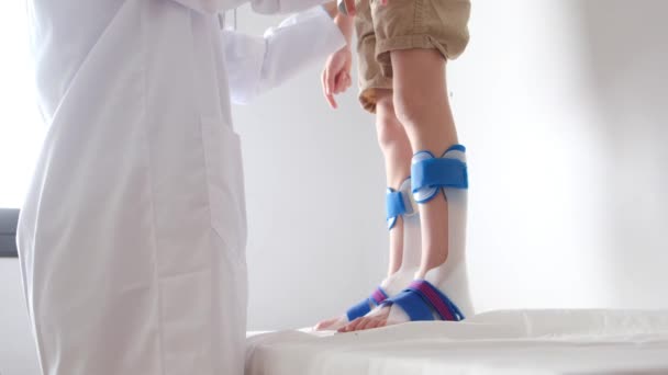 診療所の脱皮症を身に着けている少年患者脚を調べる女性医師 — ストック動画