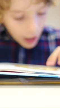 Bulanık küçük çocuk masada kitap okuyor.