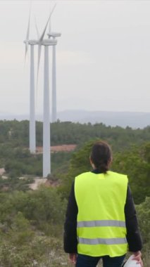 Kadın elektrik mühendisi rüzgar türbinlerini kontrol ediyor.