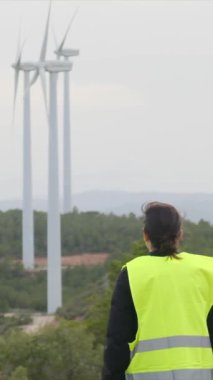 Kadın elektrik mühendisi rüzgar türbinlerini kontrol ediyor.