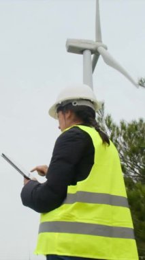 Rüzgar türbini kontrol edilirken dijital tablet kullanan kadın elektrik mühendisi