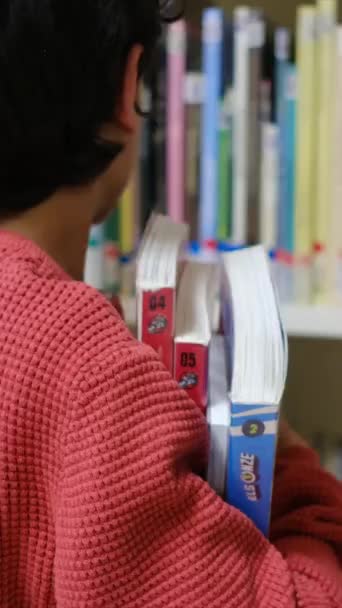 図書館で本を選択する小さな少年 — ストック動画