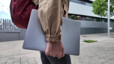 Sırt çantası ve dizüstü bilgisayarı olan bir kız öğrenci şehirde yürüyor.