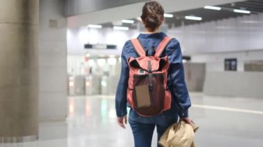 Sırt çantalı genç bir kadın metroda turnikelere doğru yürüyor..