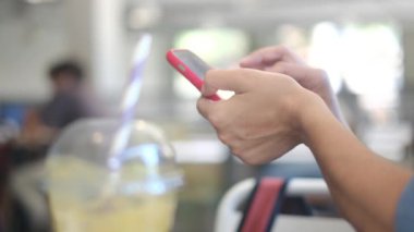 Kafede akıllı telefon kullanan genç bir kadın. 