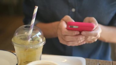 Kafede akıllı telefon kullanan genç bir kadın. 