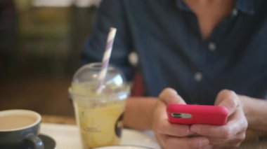 Kafede akıllı telefon kullanan genç bir kadın. 