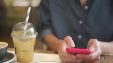 Kafede akıllı telefon kullanan genç bir kadın. 