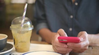 Kafede akıllı telefon kullanan genç bir kadın. 