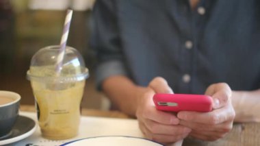 Kafede akıllı telefon kullanan genç bir kadın. 