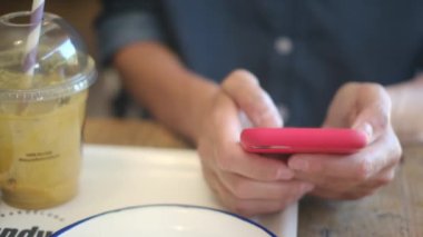 Kafede akıllı telefon kullanan genç bir kadın. 