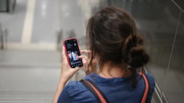 Metro istasyonunda akıllı telefon kullanan genç bir kadın. 