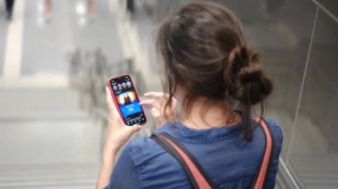 Metro istasyonunda akıllı telefon kullanan genç bir kadın. 