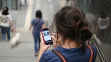 Metro istasyonunda akıllı telefon kullanan genç bir kadın. 