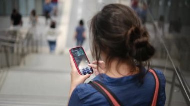 Metro istasyonunda akıllı telefon kullanan genç bir kadın. 