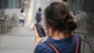 Metro istasyonunda akıllı telefon kullanan genç bir kadın. 