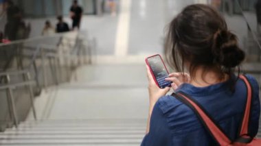 Metro istasyonunda akıllı telefon kullanan genç bir kadın. 