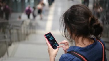 Metro istasyonunda akıllı telefon kullanan genç bir kadın. 